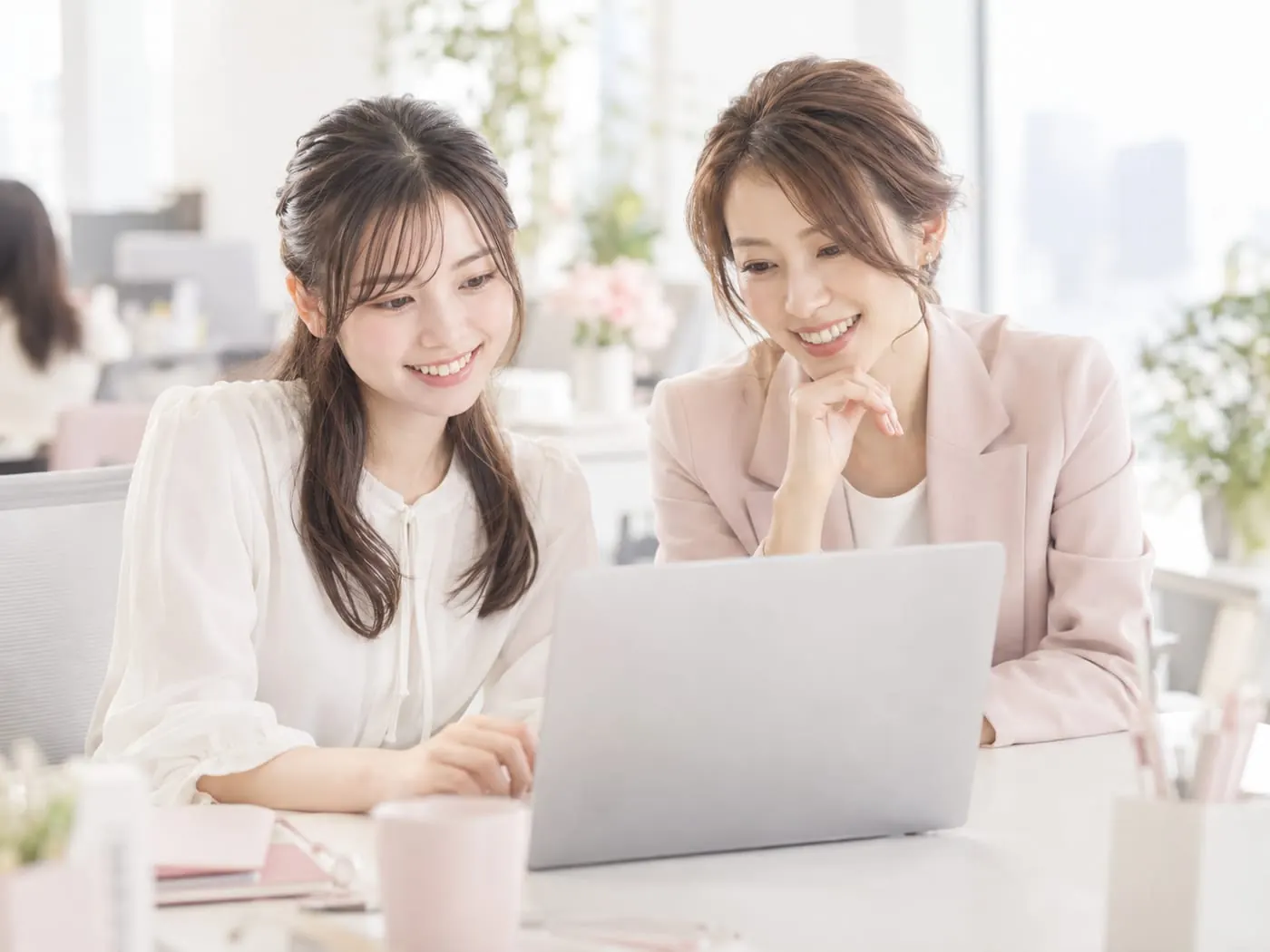 先輩と並んで笑顔でPCを見る社員